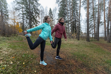 Young man and woman doing stretching exercises in the forest.