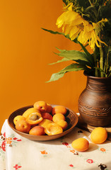 Still life with apricots and flowers shot in ethno style
