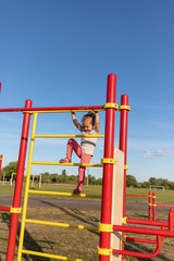 A small child goes in for sports in the stadium. hanging on the horizontal bar, on the uneven bars