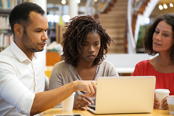 Focused people working at library. Serious adult students studying with laptop at library. Education, communication concept