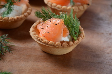Tartalets with fresh salmon, philadelphia cream cheese, olives on wooden background