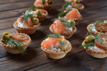 Tartalets with fresh salmon, philadelphia cream cheese, olives on wooden background