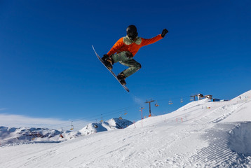 Naklejka na ściany i meble Snowboarder does a jumping trick in the snow Park