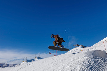 Naklejka na ściany i meble Snowboarder against the blue sky. Livigno, Italy