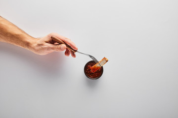 Top view of man putting steak slice in tomato sauce on white background