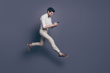 Fototapeta na wymiar Full length photo of cheerful guy get message from girlfriend read sms from smartphone enjoy jump run date wear white shirt outfit isolated over grey color background