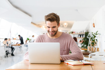 Obraz premium Image of young man working on laptop while sitting in cafe indoors
