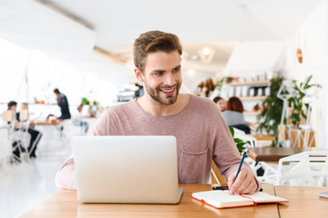Obraz premium Image of young man working on laptop while sitting in cafe indoors