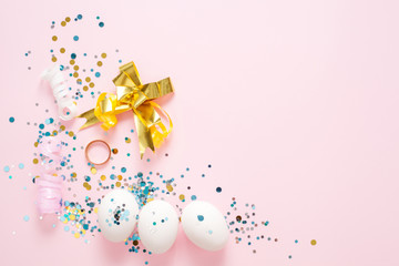 White eggs on a pink background, decorated with a gold bow, festive sparkles, with copy space. Easter concept.