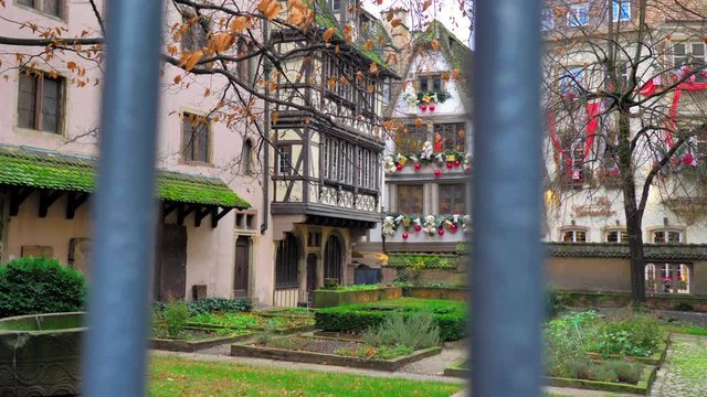 plano marcha atras atravesando reja junto a patio de Estrasburgo al atardecer de navidad