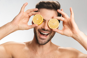Photo of cheerful half-naked man laughing and making fun with lemon