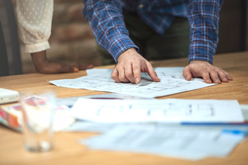 Fototapeta premium Cropped shot of professional architect and engineer discussing on the construction plan together. Architects working with blueprints in the office. Teamwork architects concept.