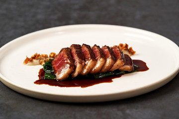 Sliced lamb meat and mashed potatoes on a white plate on gray table