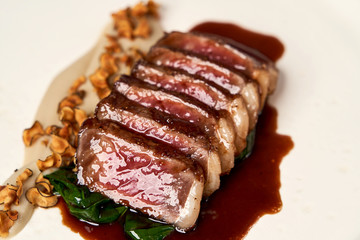 Sliced lamb meat and mashed potatoes on a white plate on gray table