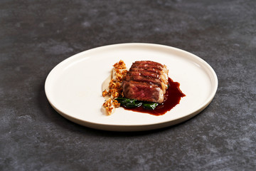 Sliced lamb meat and mashed potatoes on a white plate on gray table