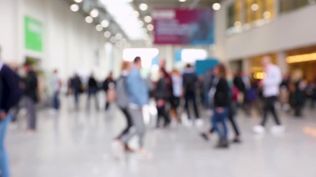 Blurred crowd of people passing by in a convention hall