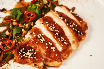 Grilled chicken fillet and baked green peppers on a white plate