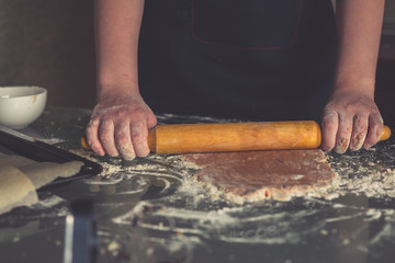 girl preparing cookies in the shape of a heart for the holiday Valentine's Day at home, in a small bakery, family business, authentic, hobby, mood, cozy. Care and love