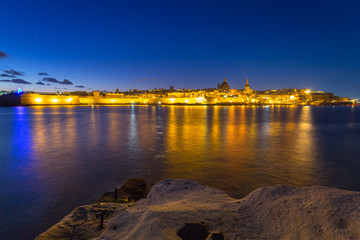 Rocky coastline of Malta and the architecture of Valletta city at night