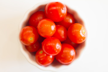 lots of cherry tomatoes in a white plate on a white background. texture. concept of fresh vegetables and healthy food. space for text. top view of tomatoes. ripe harvest.