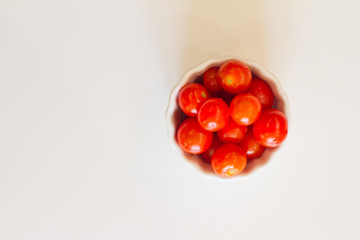 lots of cherry tomatoes in a white plate on a white background. texture. concept of fresh vegetables and healthy food. space for text. top view of tomatoes. ripe harvest.