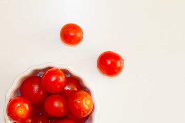Fototapeta na wymiar lots of cherry tomatoes in a white plate on a white background. texture. concept of fresh vegetables and healthy food. space for text. top view of tomatoes. ripe harvest.