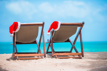 Santa Claus Hat on beach lounger with turquoise sea water and white sand. Christmas vacation concept
