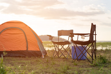 Camping tents, camp tent and chair by the river at sunset in the summer. Lifestyle concept and...