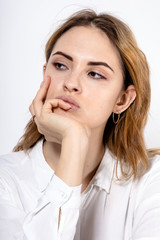 Fototapeta premium close-up portrait of a young attractive girl with a pensive look and hand in the face on a white background