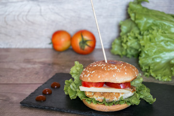Home made burger with fresh meat, tomato, cheese on black desk.