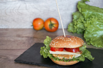 American burger with fresh meat, tomato, cheese on black desk with copy space.