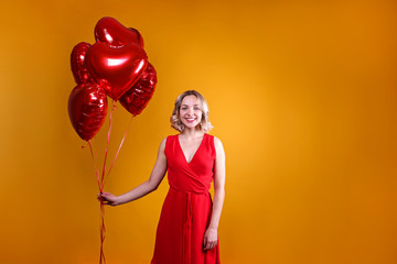 Portrait of young blonde woman posing with helium inflated air balloon. Happy valentine's day concept. Happy female with curled hair over colorful background. Close up, copy space for text.