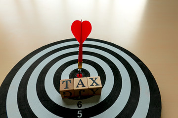 tax return concept wooden cube on dart target with red arrow