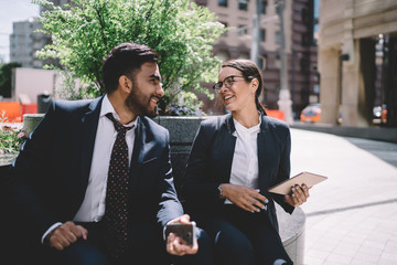 Joyful elegant woman having fun with colleague in street