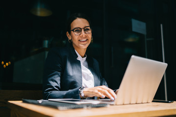 Fototapeta premium Cheerful businesswoman with laptop working in street restaurant