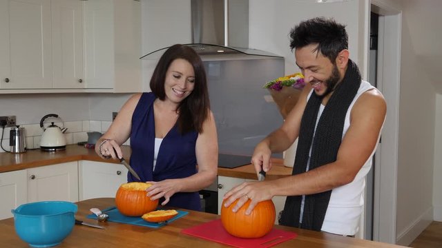 4K: A Couple Carving Pumpkins With Knives To Make Jack O Lanterns For Halloween - Slow Motion. Stock Video Clip Footage