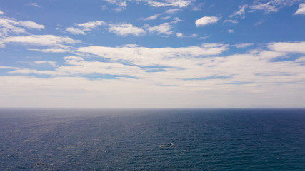 Obraz premium Tropical blue sea and blue sky with clouds. Seascape, aerial view. Flight over the sea. Summer and travel vacation concept.