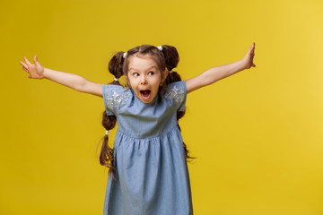 Little girl child emotions joy expression portrait. Smile admiration surprise. Childhood is happiness. The color background is yellow saturated. Place for text copy space banner. Brunette long hair 