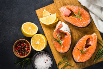 Raw salmon steak on black top view.