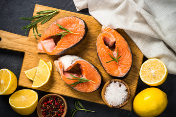 Raw salmon steak on black top view.