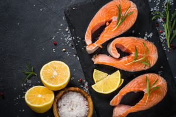 Raw salmon steak on black top view.