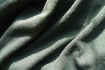 Crumpled dark green jersey fabric from above