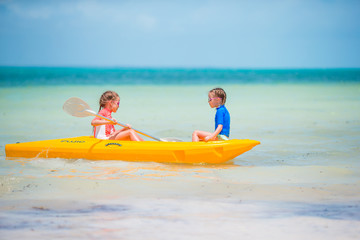 Fototapeta na wymiar Little adorable girls enjoying kayaking on yellow kayak