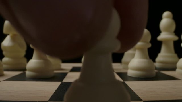 The first standard move by the E2-E4 white chess pawn on checkerboard. Macro wide angle shot with dolly sliding out. Epic beginning of the chess game
