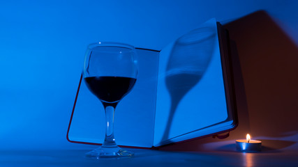 blank pages of a notebook and a glass of wine on a white background