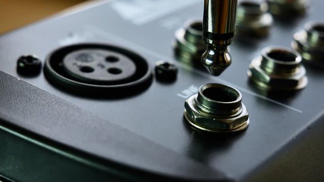 Close up of audio mixer as musician DJ plugs in 6.3 jack instrument cable. 4k