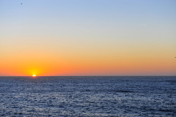 Obraz premium Scenic view of the sun going down with the deep blue ocean