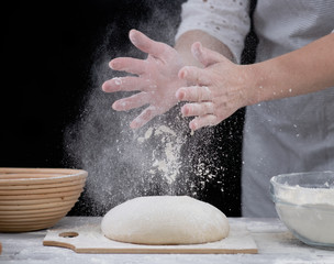 Woman sprinkl flour on a dough for cooking pastries, bread or pizza. Isolated on dark background