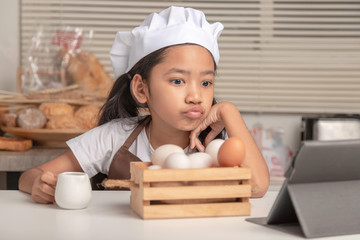 An Asian girl is watching how to make a bakery from a laptop