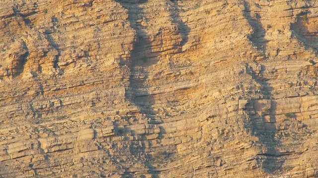 Sunlights on mountain canyon, Stone texture on a mountain face in early morning light, zooming out of sedimentary mountain limestone rocks texture , Ras Al Khaimah  , United Arab emirates 